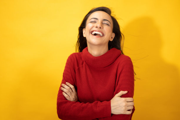 照片的年轻妇女在冬天穿站在黄色背景股票照片图片下载