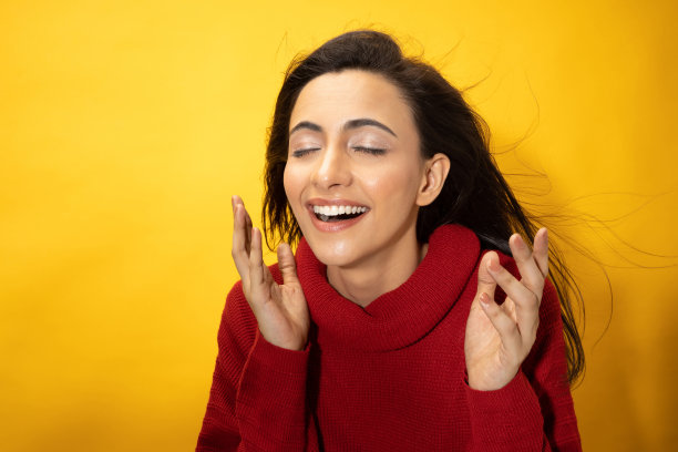 照片的年轻妇女在冬天穿站在黄色背景股票照片图片下载