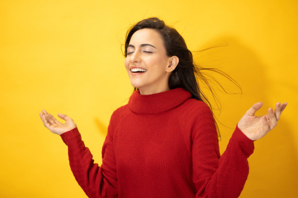 照片的年轻妇女在冬天穿站在黄色背景股票照片图片下载