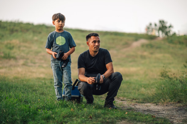 一个男孩和他的父亲在大自然中拿着遥控器的照片。图片下载