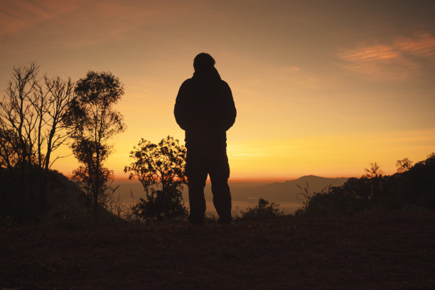景观和旅行的概念与单独的自由职业者站着，看日出与山的背景层图片下载