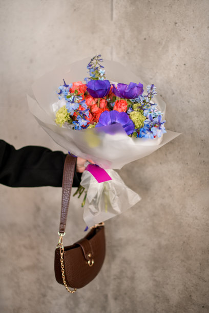 一位女士手里拿着一束紫色的花和一个小手提包图片下载