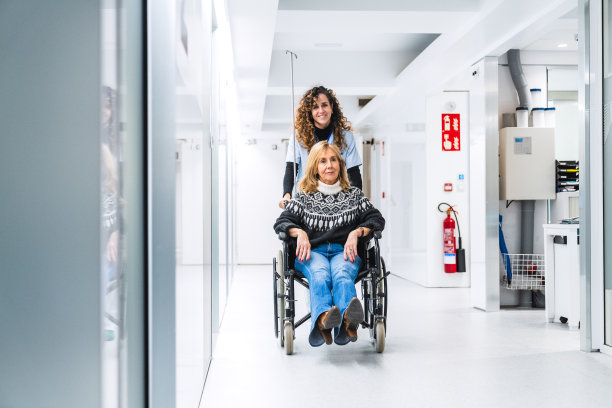 一名护士在医院大厅用轮椅搬运病人的正面照片图片下载