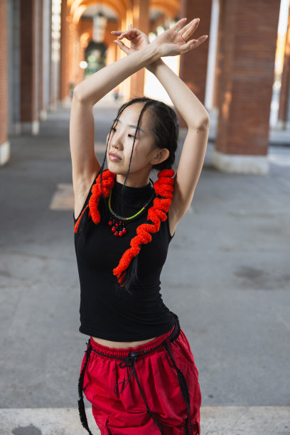 一个亚洲女人在城市中穿着城市服装跳舞的姿势的肖像，垂直的图片图片下载