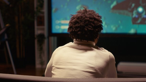 一名男子使用云游戏服务，在超宽电视屏幕上玩高要求的科幻视频游戏图片下载