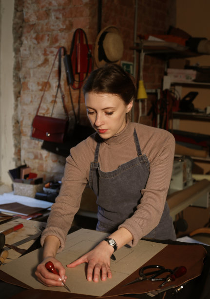 年轻女子在包制作工作室工作，裁剪细节图片下载
