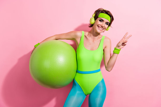 照片正面女士普拉提交叉健身女运动员练习与fitball使v标志孤立柔和的颜色背景图片下载