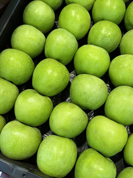 超市货架上的水果的全画幅图像，塑料板条箱里有一堆抛光的绿色史密斯奶奶苹果(家苹果)在超市的当地新鲜农产品通道出售，高架视图图片下载