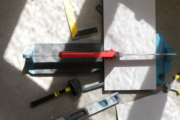 使用标准的手动瓷砖切割机切割瓷砖。瓷砖在浴室中逐步安装的过程。DIY家居装修。图片下载