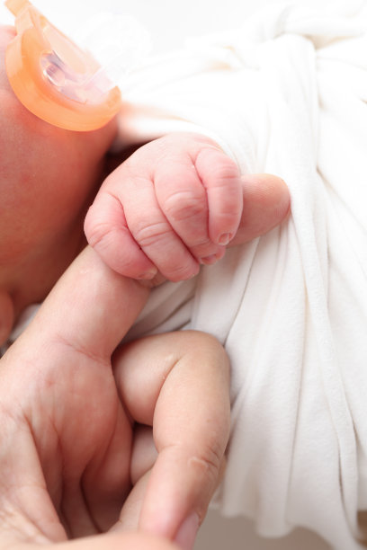 宝宝的小手、头、耳朵和妈妈的手掌特写。新生儿出生后紧紧握住父母的手指，白色背景的微距照片。家庭和家庭概念。医疗儿科学图片下载