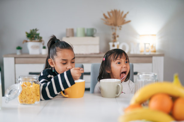 两姐妹在一起吃早餐麦片加牛奶的照片图片下载