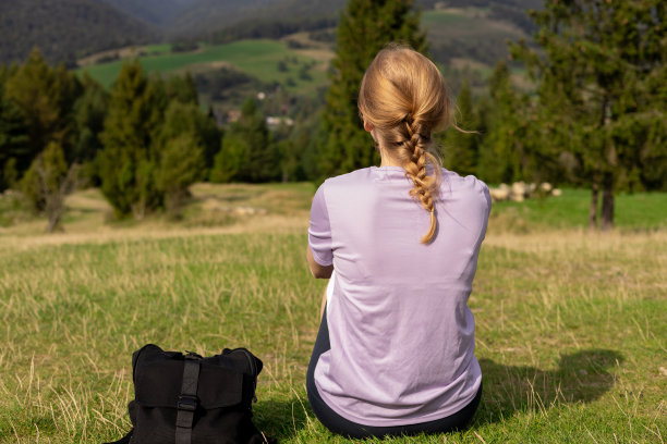 徒步旅行后，穿着运动服休息的妇女的后视图。旅行和积极的生活方式理念。30多岁的女孩在山顶欣赏山谷美景，户外活动图片下载