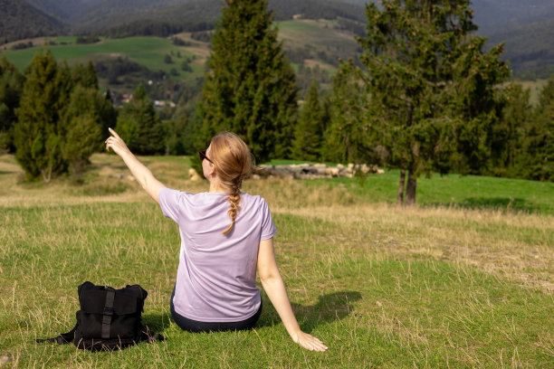徒步旅行后，穿着运动服休息的妇女的后视图。旅行和积极的生活方式理念。30多岁的女孩在山顶欣赏山谷美景，户外活动图片下载