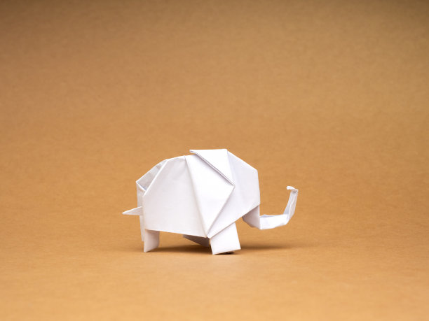 一个白色的大象纸站孤立的生态棕色牛皮纸背景。折纸艺术手工风格上的回收纸。爱护大象，爱护动物的理念。图片下载