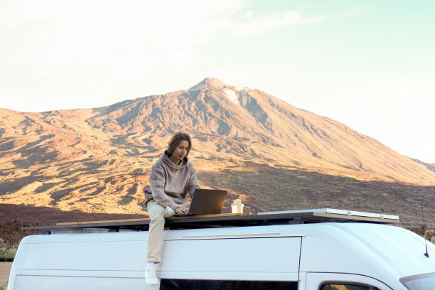 年轻人在面包车顶上用笔记本电脑工作，背景是泰德山图片下载
