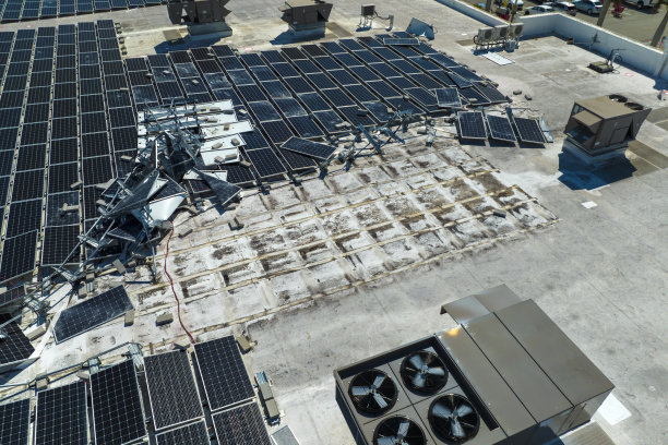 被飓风伊恩摧毁的俯视图安装在工业建筑屋顶上的光伏太阳能电池板产生绿色生态电力。佛罗里达自然灾害的后果图片下载