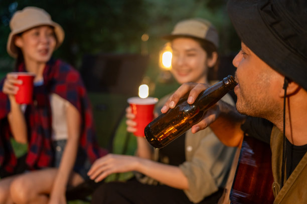 干杯!一群亚洲人朋友在大自然中露营，用软饮料和啤酒举杯祝酒。户外聚会在露营地自然森林背景在假日周末假期图片下载