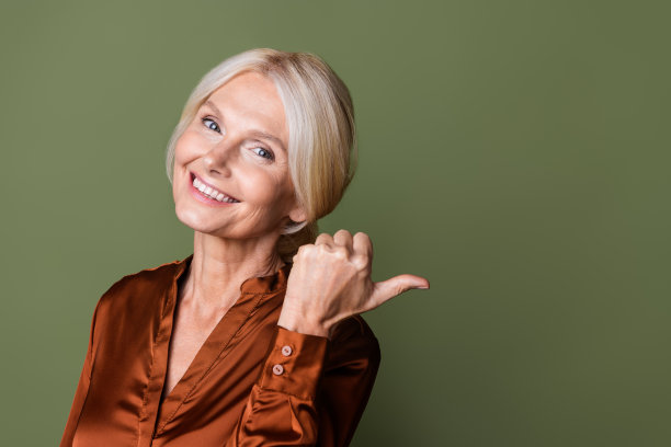 照片肖像漂亮的退休女性点宣传空空间穿着时尚的丝绸棕色服装孤立的卡其色背景图片下载