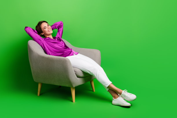 铺设扶手椅的女人房地产经纪人铺设扶手椅等待客户隔离在绿色背景的全长照片图片下载