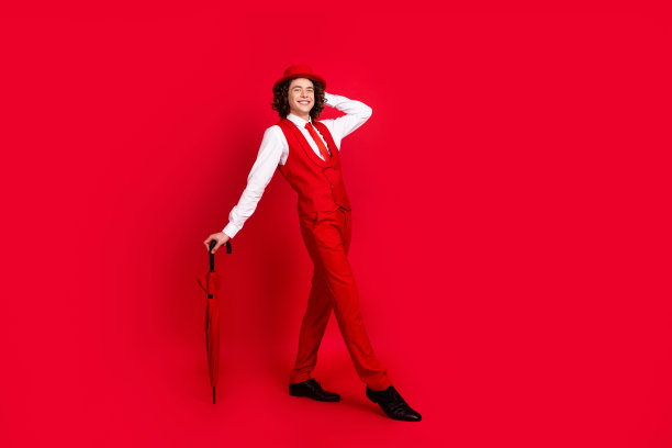 豪华模特的全身长度的照片少年男子在西装背心与遮阳伞触摸帽子表演演唱会孤立的红色背景图片下载