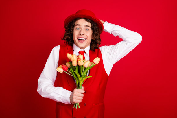 年轻的男友惊讶的照片不知道如何给他的女朋友新鲜的郁金香邀请约会孤立的红色背景图片下载
