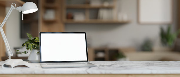 在舒适的家庭办公室里，豪华的白色大理石桌子上放着一台白色屏幕的笔记本电脑模型。图片下载