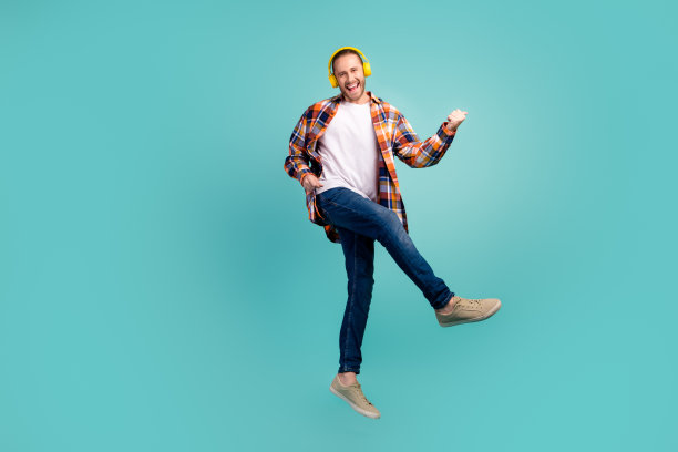 全长照片的酷男子飞行听摇滚音乐在耳机发挥想象吉他孤立的绿松石色背景图片下载