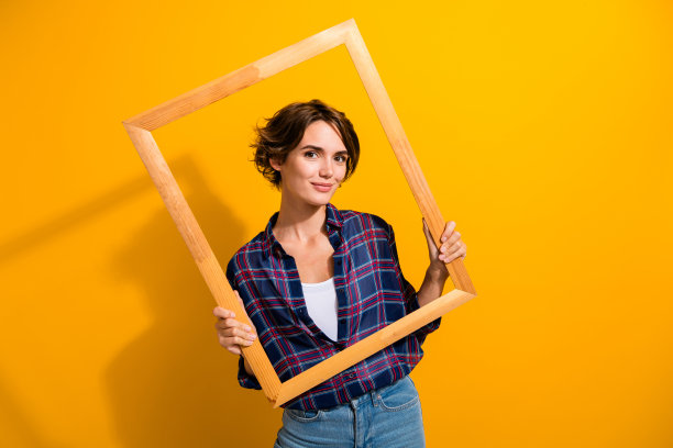 照片的华丽可爱的女人与波波头穿着格子衬衫在木制相框孤立的黄色背景图片下载