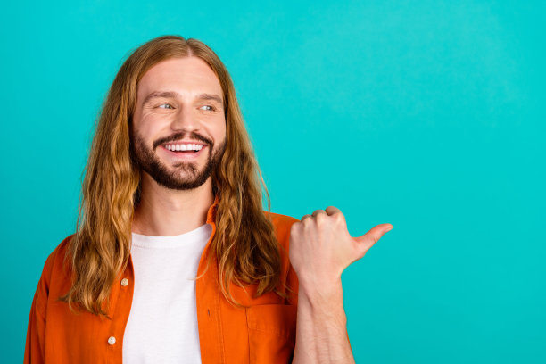 照片积极的年轻人在橙色衬衫表明拇指空白空间新的品牌战略营销孤立的蓝色背景图片下载