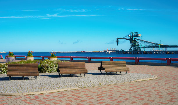 在港口的背景下，沿着河边散步和放松的地方。Ventspils,拉脱维亚。舒适的木质长椅。有选择性的重点。图片下载