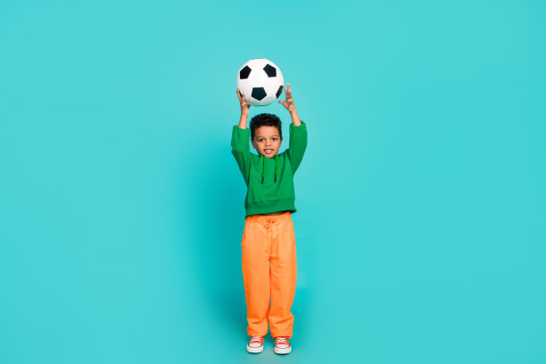 搞笑可爱的男孩职业足球运动员训练世界杯联赛在青色背景孤立的全长照片图片下载