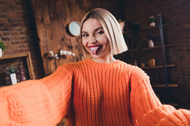 照片正面可爱的女士露齿微笑，露出舌头拍自拍照记录视频空闲时间平在室内图片下载