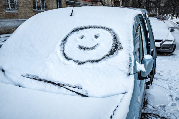 笑脸(符号)画在汽车挡风玻璃雨刷上方的雪上。冬天，交通概念。图片下载