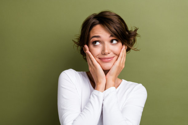 照片上的小女孩摸着脸颊看起来很可爱，空白的空间里穿着时尚的白色衣服，孤立在卡其色的背景上图片下载