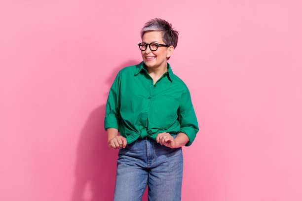 照片肖像有吸引力的退休妇女摆出领带蝴蝶结衬衫，穿着时尚的绿色衣服孤立在粉红色的背景图片下载