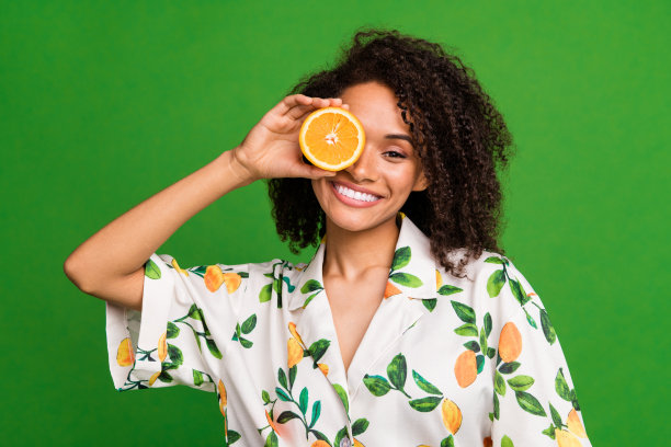 照片的俏皮漂亮的女人穿着印花衬衫上升橙色半闭眼睛孤立的绿色背景图片下载