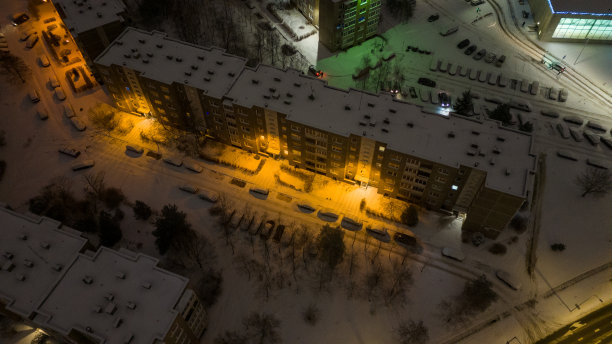 无人机拍摄的建筑物附近的停车场和积雪覆盖的汽车在冬天的早晨图片下载