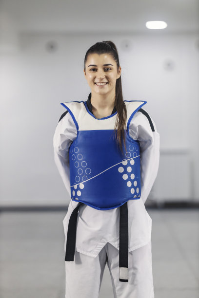 带黑带的跆拳道女孩站在武术学校，对着镜头微笑。图片下载