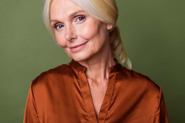 照片肖像漂亮的退休女性护肤程序迷人的穿着时尚的丝绸棕色服装孤立的卡其色背景图片下载