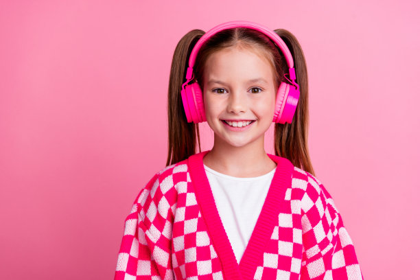照片甜美闪亮可爱的女孩穿着时髦的衣服，听着旋律音响立体声空的空间孤立在粉红色的背景图片下载