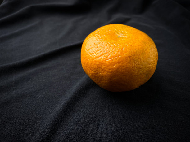 一个成熟的橙子的照片孤立在黑布背景。空白复制文本空间。图片下载