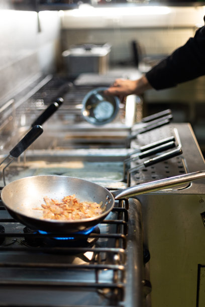 厨师在餐厅用煎锅烹饪意大利面图片下载