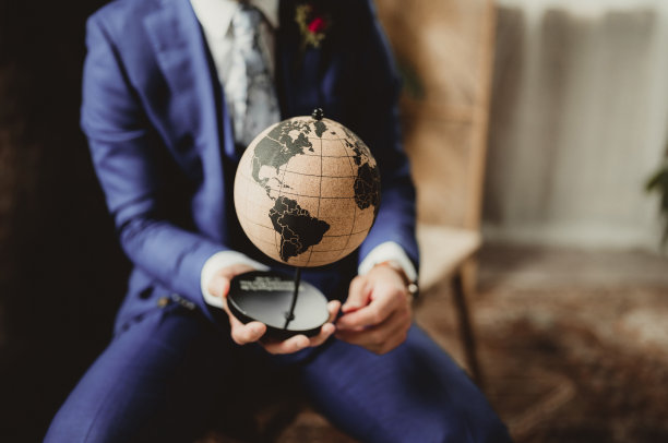 西装革履的男子手持老式世界地球仪图片下载