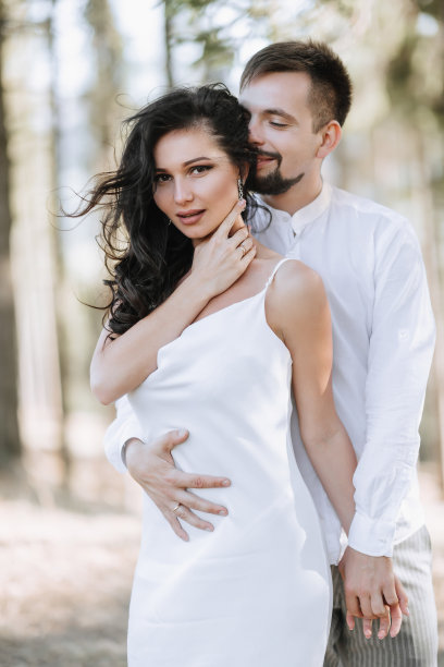 年轻幸福的情侣拥抱微笑，在山上玩得很开心。高质量的照片。一个穿着漂亮白裙子的女孩。肖像照片图片下载