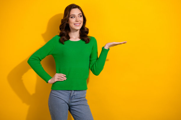 照片中漂亮可爱的女人穿着绿色的衣服，广告质量品牌产品的空白空间孤立在黄色的背景图片下载