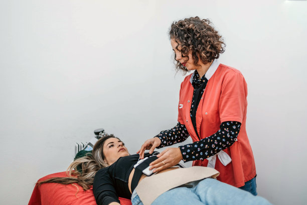 治疗师将激光垫放在女性的腹部。图片下载