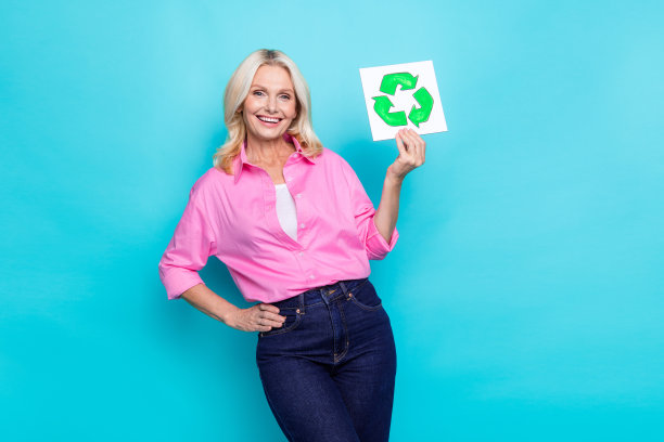 有吸引力的退休妇女的照片肖像拿着回收标志，穿着时髦的休闲服装，孤立在青色背景上图片下载