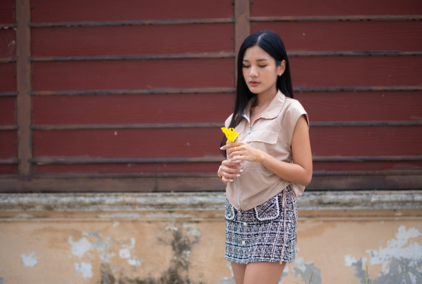 一个穿着复古连衣裙的年轻女子独自站在墙边，手里拿着鲜花，一脸悲伤。很不高兴图片下载