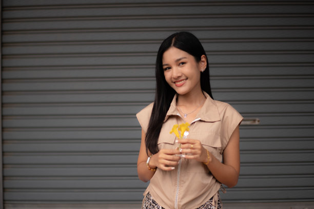 一位穿着复古衣服的年轻女子手里拿着一朵黄色的花，欣赏着。然后转身看着镜头图片下载