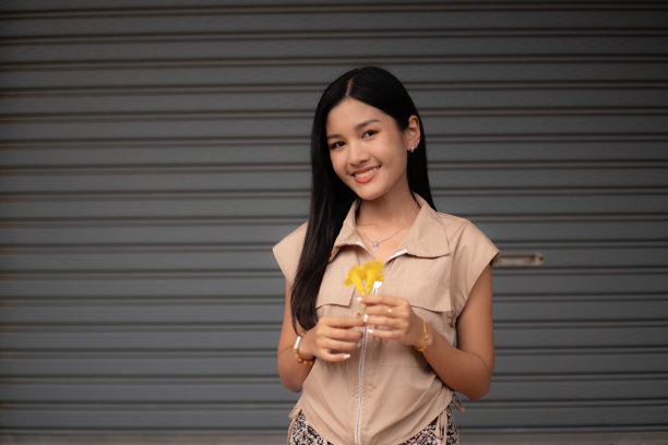 一位穿着复古衣服的年轻女子手里拿着一朵黄色的花，欣赏着。图片下载